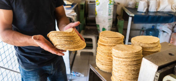 young man selling tortillas of nixtamal in typical mexican shop