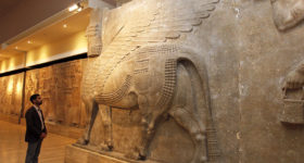 A man looks at ancient Assyrian human-headed winged bull statues at the Iraqi National Museum in Baghdad