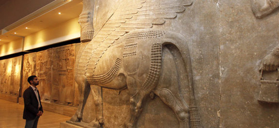 A man looks at ancient Assyrian human-headed winged bull statues at the Iraqi National Museum in Baghdad