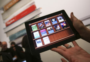 File photo of a woman holding up an iPad with the iTunes U app after a news conference introducing a digital textbook service in New York