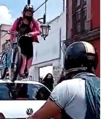 Ciclista repartidora pasa encima de un auto que bloqueó la iclovía en Querétaro